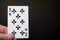 Man hand holding playing card eight of clubs isolated on black background with copyspace abstract
