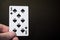 Man hand holding playing card eight of spades isolated on black background with copyspace abstract