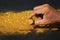 Man hand holding pure gold minerals with golden light on black background, investment and business concept