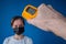 Man hand holding pyrometer, measuring temperature of woman in medical face mask