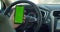 Man hand holding a smartphone with green blank screen in the electric car for direction, massage, location, business