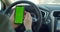 Man hand holding a smartphone with green blank screen in the electric car for direction, massage, location, business