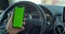 Man hand holding a smartphone with green blank screen in the electric car for direction, massage, location, business