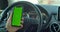 Man hand holding a smartphone with green blank screen in the electric car for direction, massage, location, business