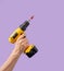 Man hand holds Brushless Cordless Combi Drill that comes from corner on purple color background