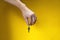 Man hand holds hanging key on iron ring on yellow background with his fingers. Hospitality or expression of trust.
