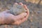 a man hand holds a small gray piece of stone