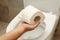 Man hand holds toilet paper on toilet bowl background