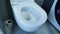 Man hand lifts toilet lid, close up. Male lifting toilet lid in bathroom with grey tiles on walls and floor. Side view of bathroom