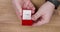 Man hand opening a small red box with engagement diamond ring