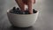 Man hand pick ripe blueberries from white bowl on oak table