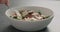 Man hand pick salad with arugula, prosciutto in white bowl