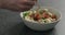 Man hand pick salad with mozzarella, cherry tomatoes and frisee leaves in white bowl on terrazzo surface