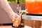 Man hand pouring fresh sorbet fruit juice or alcohol punch from drinking tank machine at party
