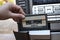 Man hand putting cassette into old fashioned audio tape player on desk wood background