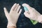 man hand in rubber surgical gloves holding antiseptic hand sanitizer on dark background. alcohol sanitizers hand hygiene corona