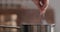 man hand salting bopiling water for pasta in saucepan closeup