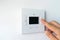 Man hand setting the room temperature on a modern programmable thermostat water heater boiler. Smart home.