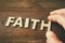 Man hand spelling the word FAITH from wooden letters, retro style image