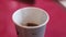 Man hand stirs coffee Americano in a paper lilac glass with a wooden stick