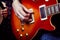 A man hand on the strings of a red guitar. Long fingers play the electric guitar in the recording Studio. Life style from the