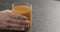 Man hand take glass of fresh sea buckthorn juice from concrete surface