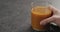 Man hand take glass of fresh sea buckthorn juice from concrete surface