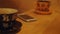 Man hand takes mobile phone from wooden desk. On the table are cups of coffee and phones. Close-up