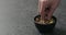 Man hand takes pistachio kernels from black bowl on terrazzo surface