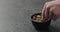 Man hand takes pistachio kernels from black bowl on terrazzo surface