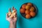 Man hand with tangerine segments and plate with oranges, blue background