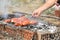 man hand turns frying grill sausages on skewers on fire. Selective focus, smoke