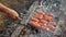 man hand turns frying grill sausages on skewers on fire. Selective focus, visible smoke