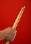 Man hand with two drumsticks over red