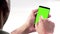 Man hand using a smart phone with chroma key on white background behind view, green screen
