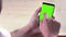 Man hand using a smart phone with chroma key on wood background, green screen, lifestyle communication