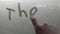 Man hand write on the foggy window glass word inscription `the end`.