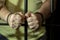 A man in handcuffs in a cell behind bars. Concept: a prisoner in a courtroom, a court sentence to a convicted person, a prison ter