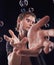 Man, hands and bubbles in studio for magic, art performance or creative show by black background. Model, artist and soap