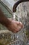 Man hands catching water from a stone fountain.