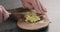 Man hands chopping fresh ginger root with knife on olive wood board