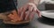 Man hands chopping salted trout with knife on olive wood board