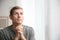 Man with hands clasped together for prayer near window