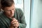 Man with hands clasped together for prayer near window