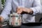 Man hands counting expenses banknotes of euro cash from glass jar in the piggy bank on calculator. Close up of hands