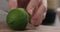 Man hands cutting lime in half with knife