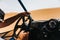 Man hands driving a buggy in the desert dunes.