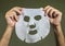 Man hands holding beauty paper facial mask isolated on even background in face skin care concept