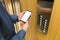 Man hands holding blank screen mobile phone next to elevator control panel