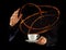 Man hands holding porcelaine cup with splashing liquid of coffee or tea, isolated on black backround